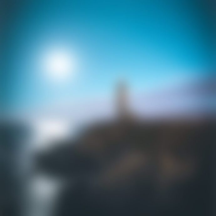 Blurry lighthouse on coastal cliff at sunset