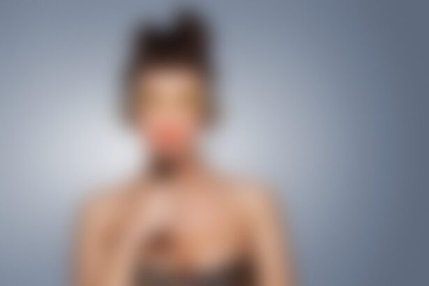 Blurred person holding red object near mouth