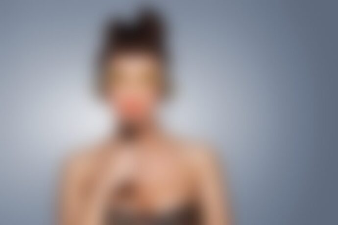 Blurred person holding red object near mouth