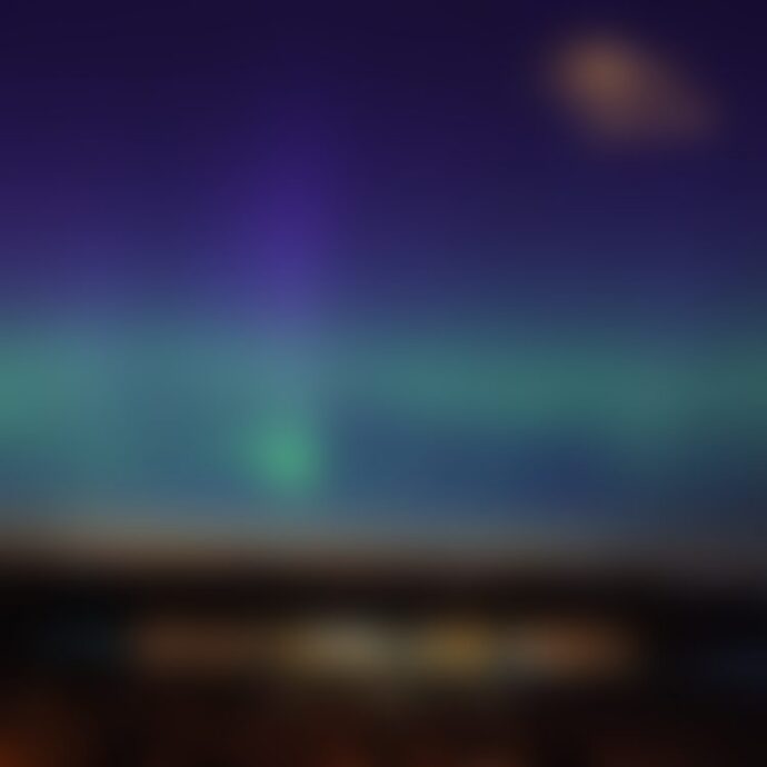 Blurred aurora borealis over coastal night lights