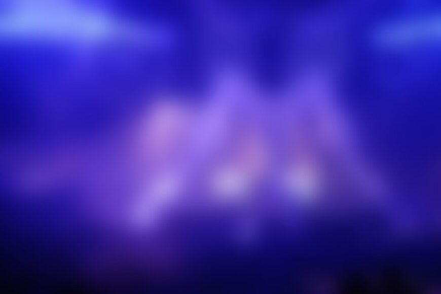 Blurry performers on purple-blue lit stage