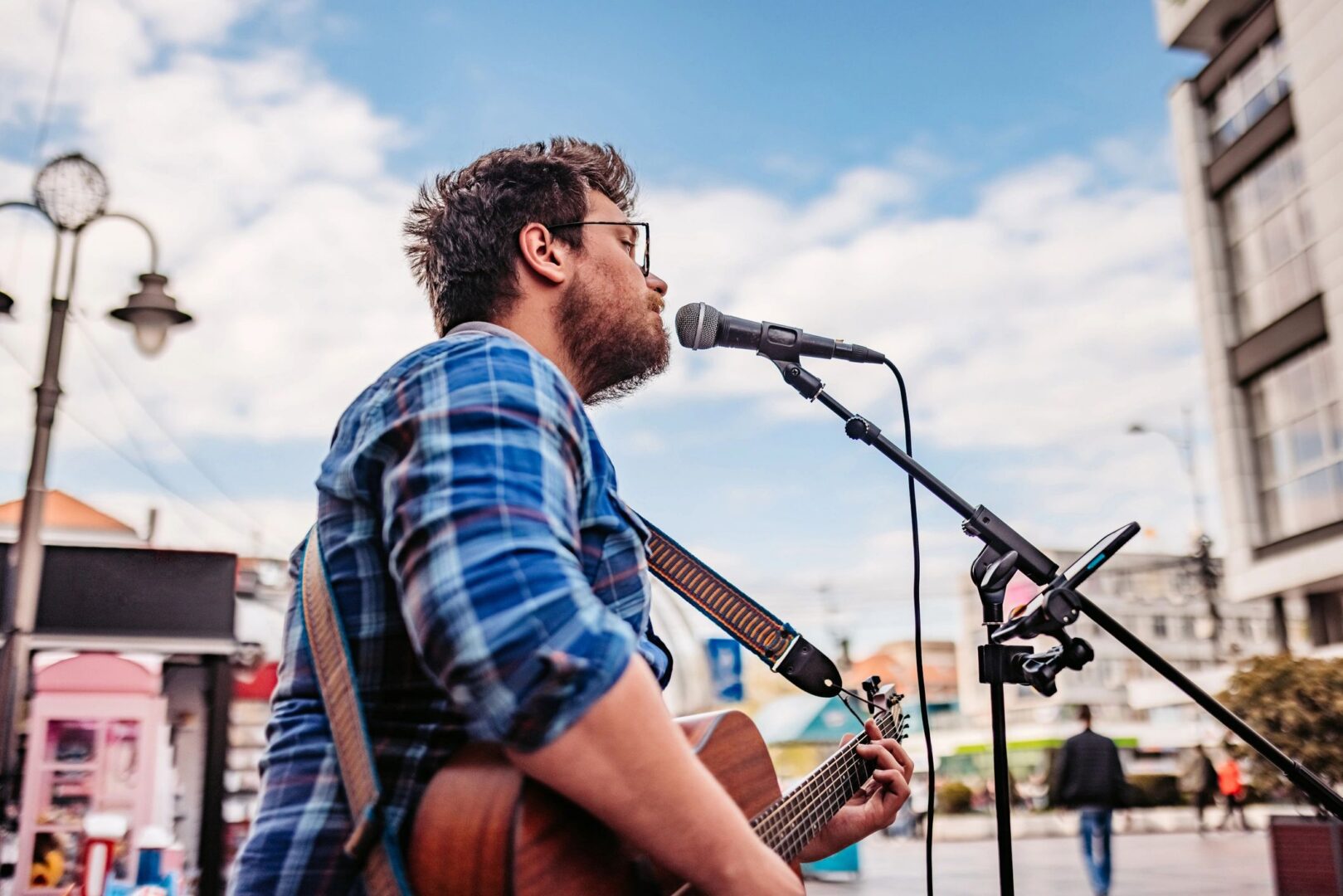 Musician singing and playing guitar on stage outdoors.