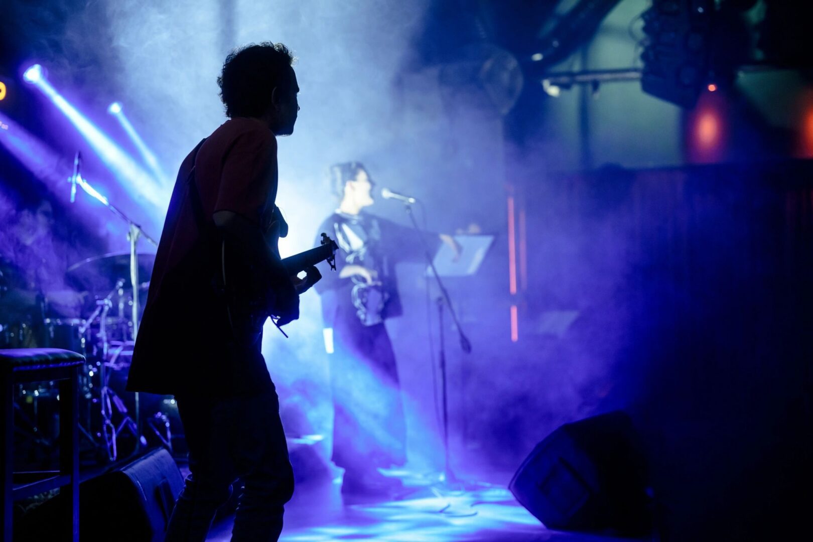 Musicians perform on a dimly lit, foggy stage with blue lighting.