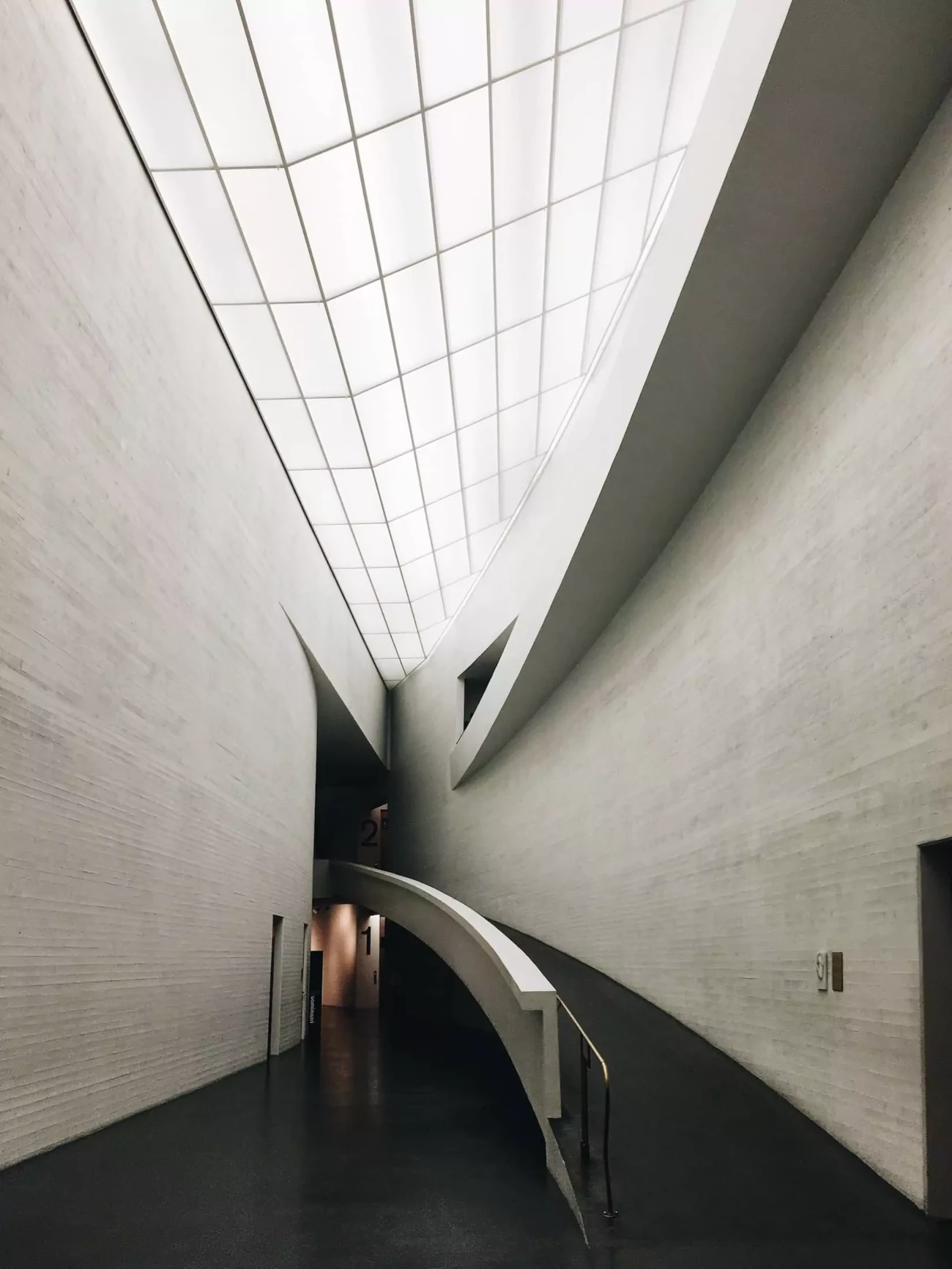 Modern architectural interior with curved pathway and large skylight.