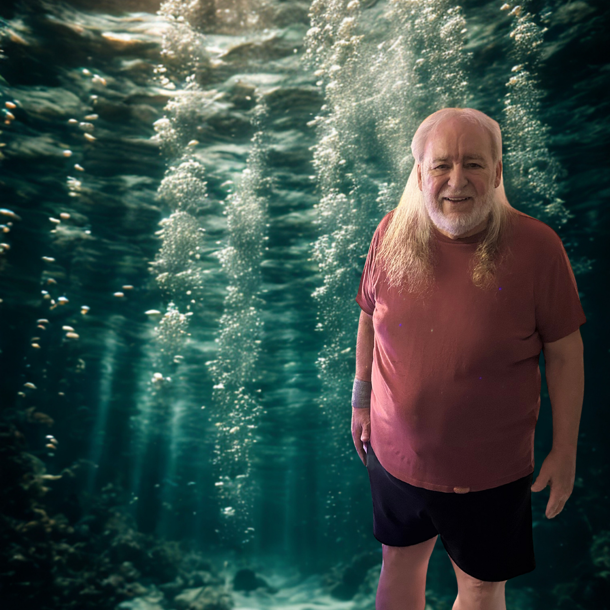Smiling man stands in underwater environment with sun rays filtering through water.